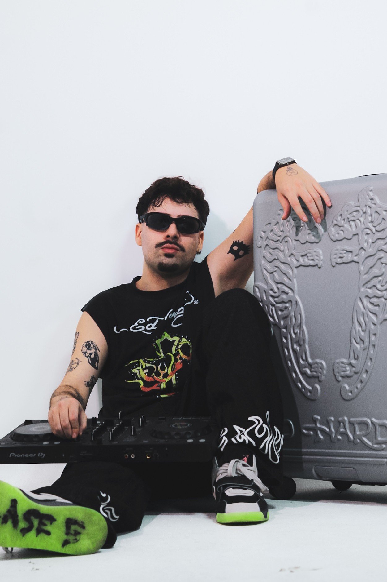 DZ The Surfer, DJ de Osasco, sentado no chão com controladora Pioneer DJ e mala prateada